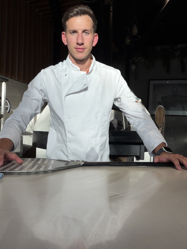 Matteo in his white chef jacket at the pizza counter